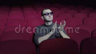 3着3D眼镜的帅哥坐在黑色电影院舒适的红色椅子上鼓掌